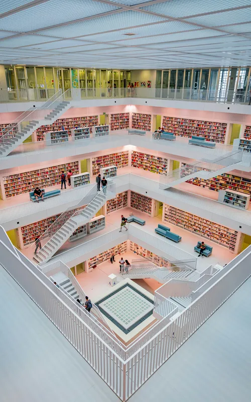 Modernes Bibliotheksinterieur mit abgestuften Bücherregalen und Treppen.